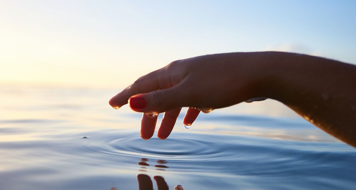 Person tippt ihre Fingerspitze in das Wasser im Gardasee Hotel